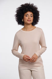 Woman wearing a beige long-sleeve crew neck top. 
