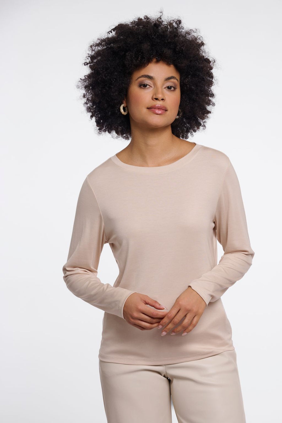 Woman wearing a beige long-sleeve crew neck top. 
