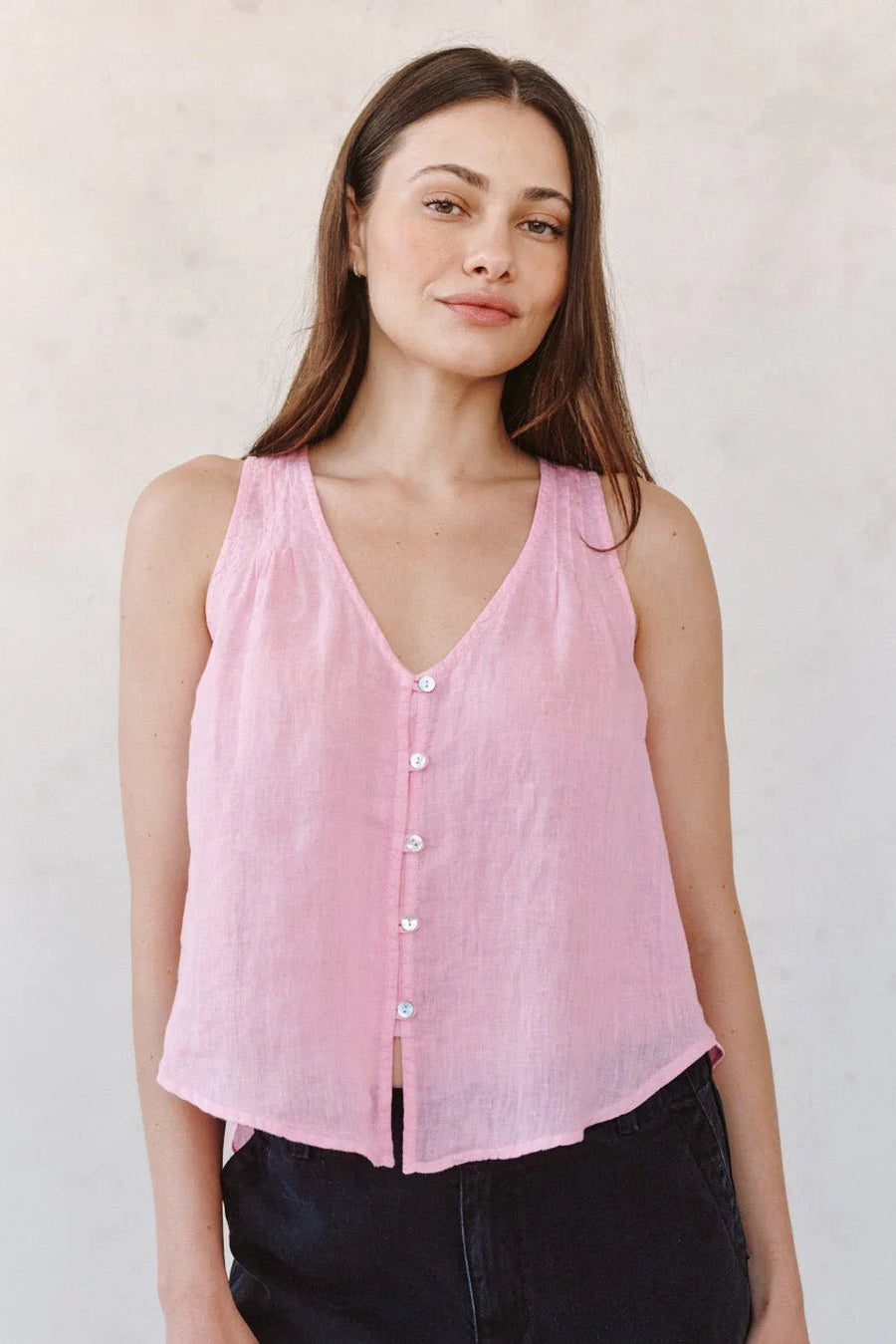 Woman wearing a pink sleeveless V-neck button-front blouse, front view