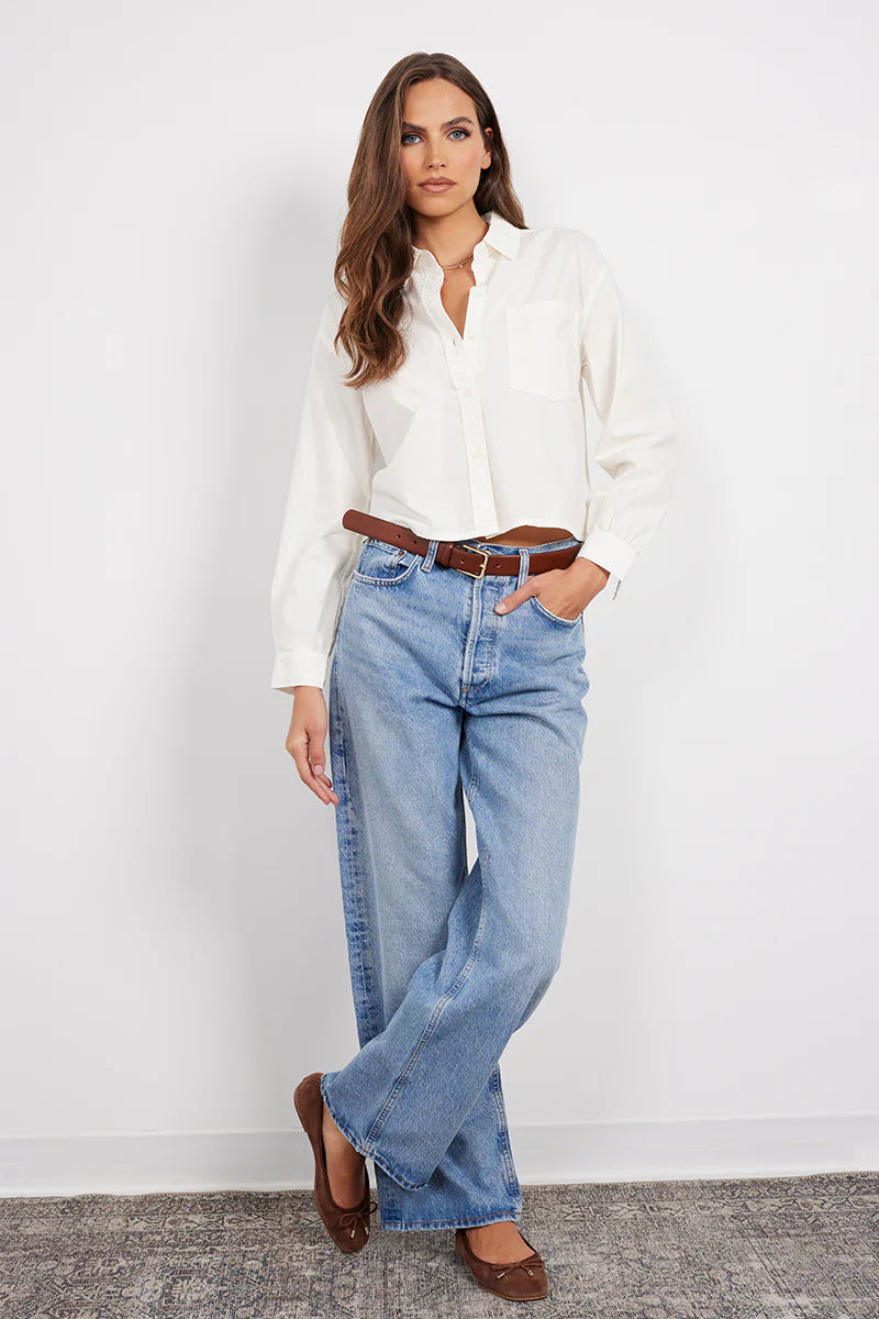 Woman wearing a white long-sleeve button-up shirt with a relaxed fit and chest pocket, front