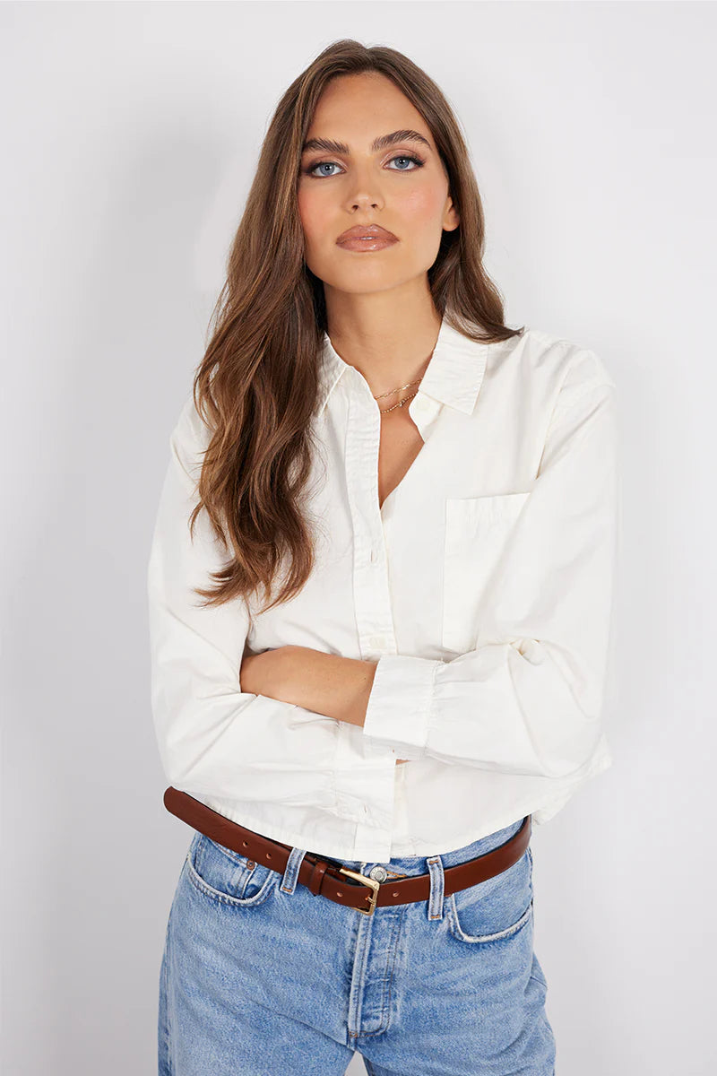 Woman wearing a white long-sleeve button-up shirt with a relaxed fit and chest pocket, front