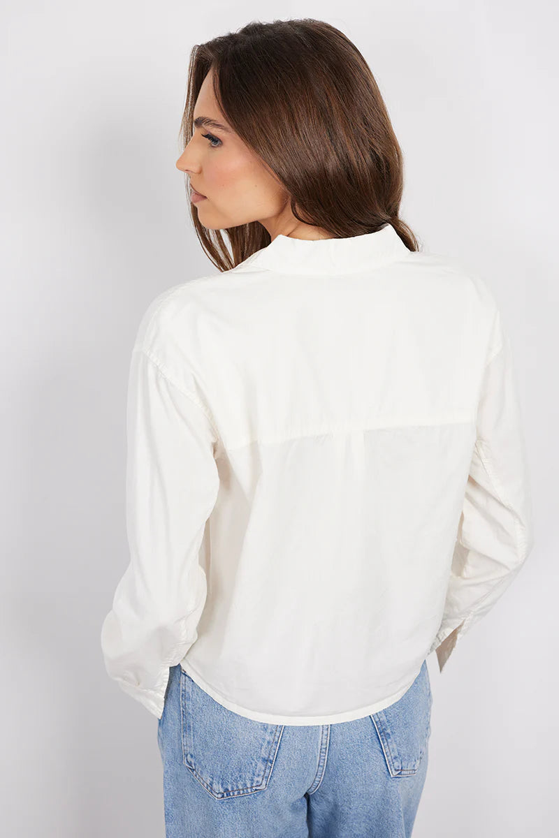 Woman wearing a white long-sleeve button-up shirt with a relaxed fit and chest pocket, back