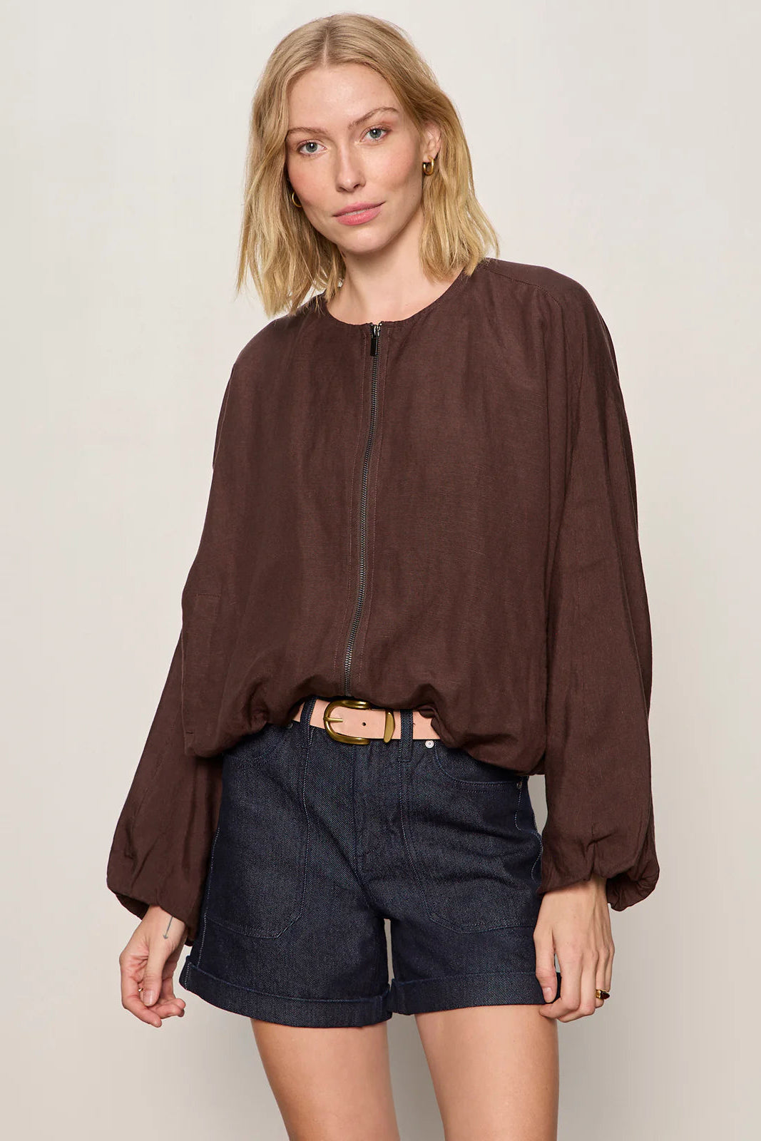 Woman wearing a lightweight rich chocolate brown bomber-style jacket with a relaxed fit. Features a zip-front closure, round neckline, dolman sleeves, elastic cuffs and waistband, and two front slant pockets, front