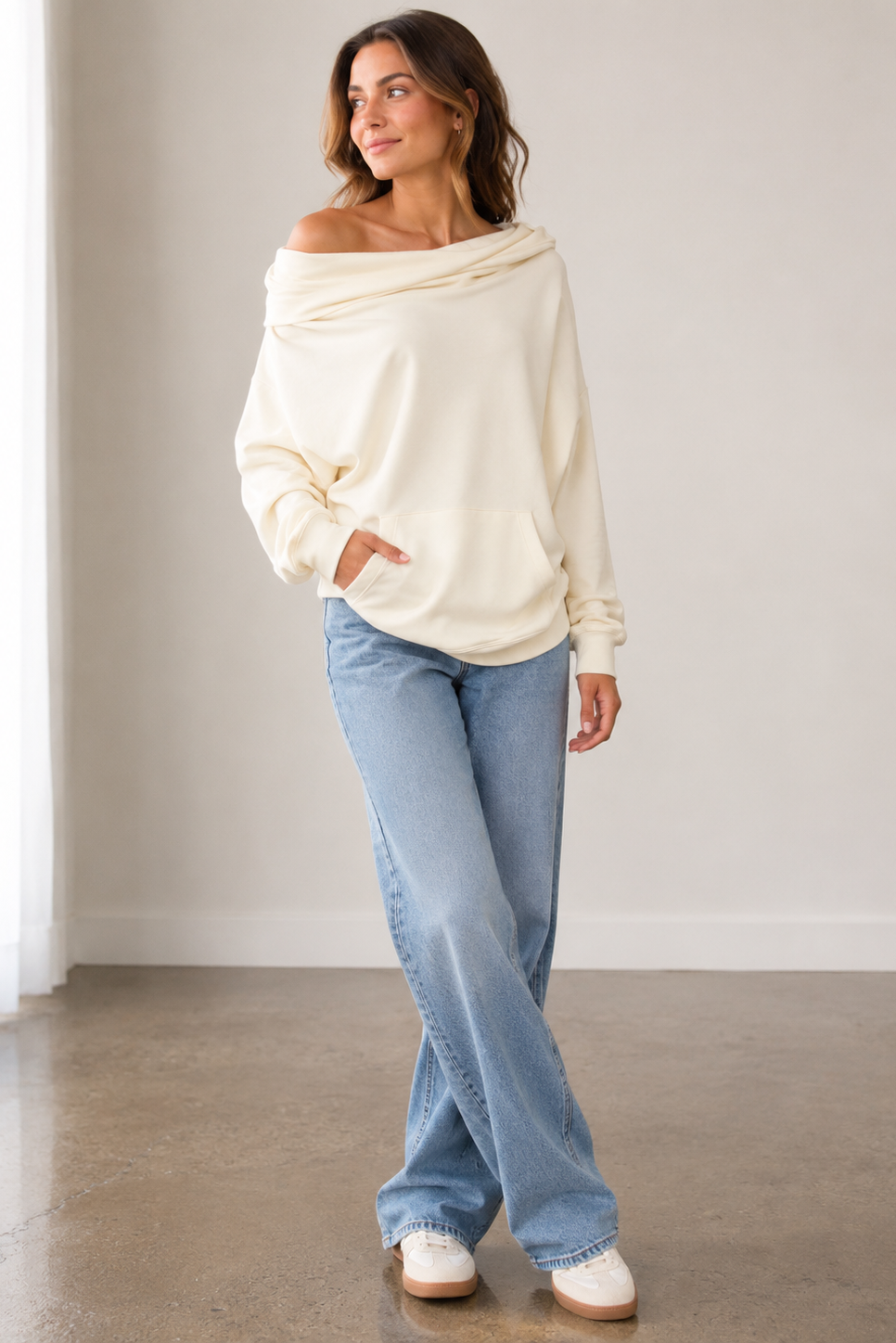 A woman modeling a cream off-the-shoulder long-sleeve sweatshirt
