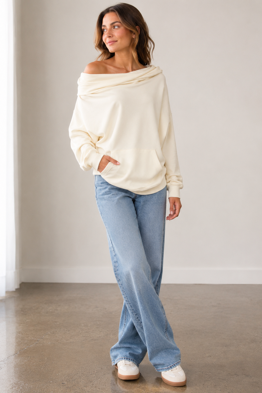 A woman modeling a cream off-the-shoulder long-sleeve sweatshirt