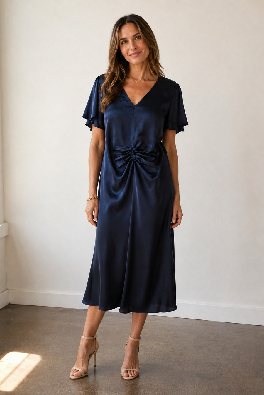model wearing a navy ruched midi dress with rucheing in the middle 