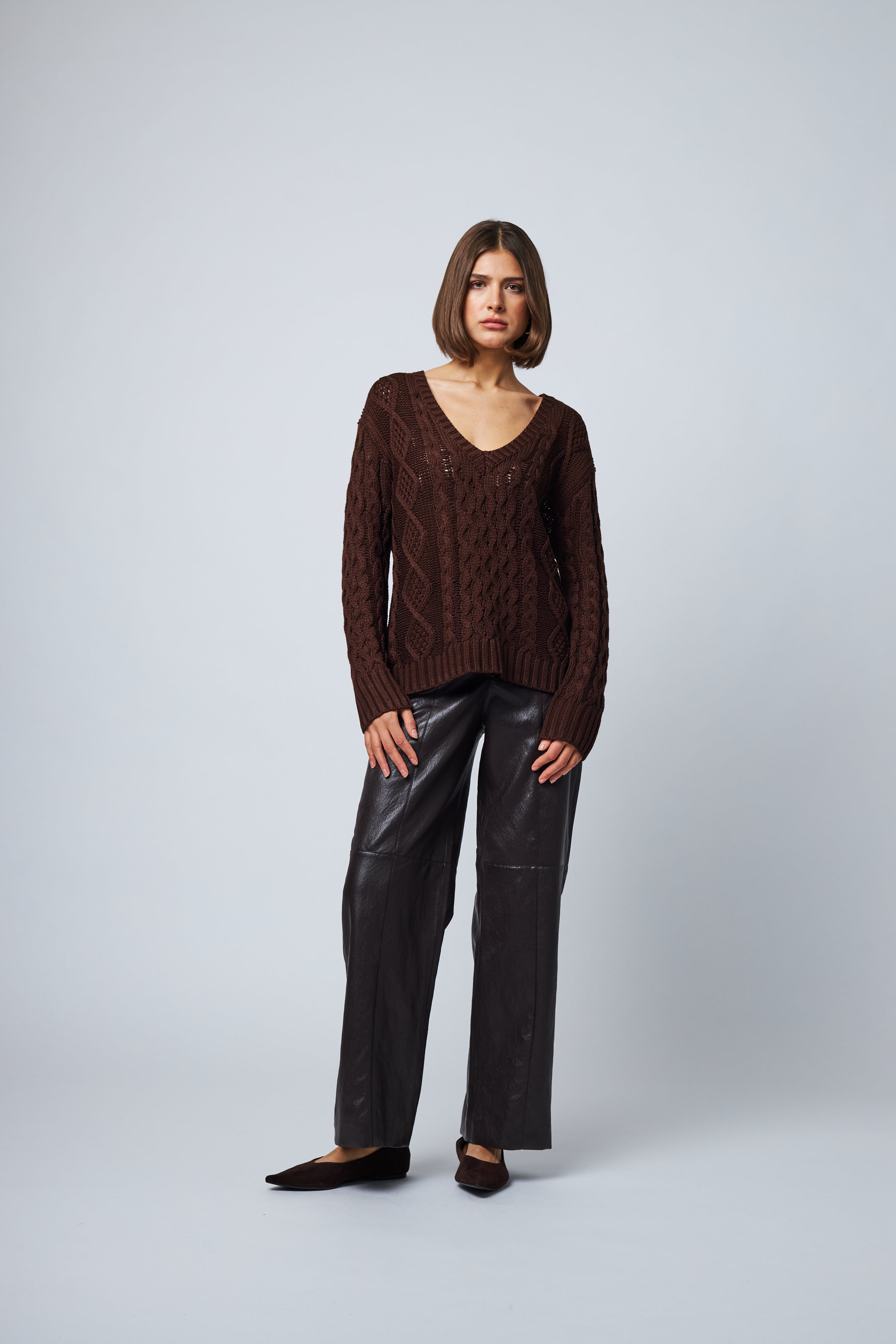 model wearing brown v neck cable knit sweater with a relaxed fit 