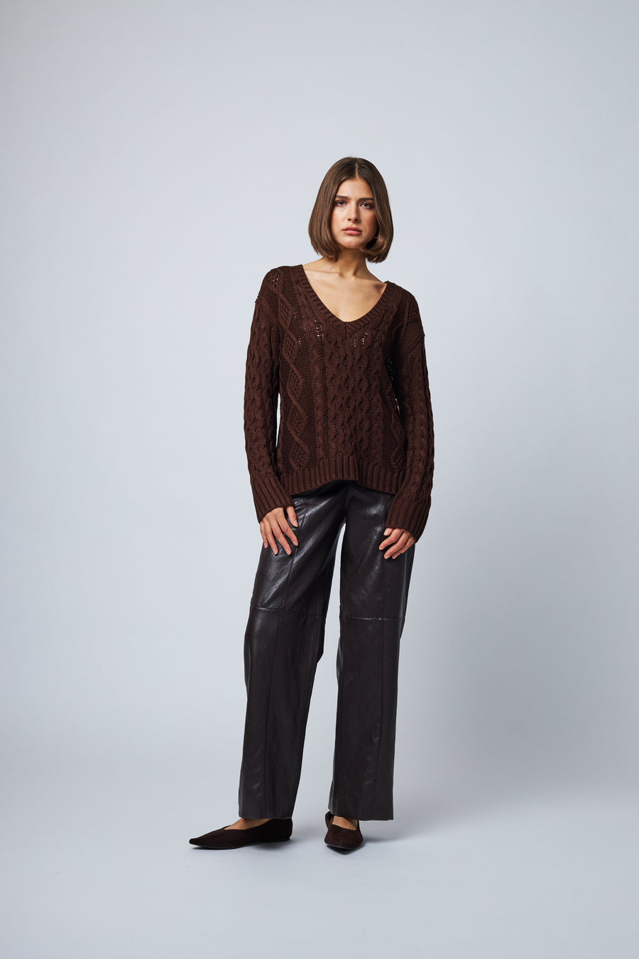 model wearing brown v neck cable knit sweater with a relaxed fit 