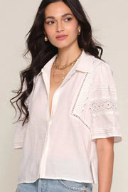 Woman wearing a off white blouse with lace details, front