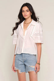 Woman wearing a off white blouse with lace details, front