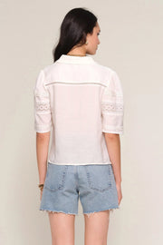 Woman wearing a off white blouse with lace details, back