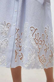 Woman wearing a light blue pinstripe short-sleeve shirt dress with a belted waist and embroidered hem, detailed view