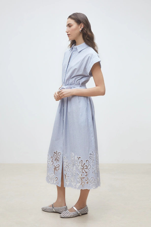 Woman wearing a light blue pinstripe short-sleeve shirt dress with a belted waist and embroidered hem, side view