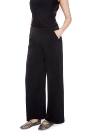 Side view of a woman wearing matching black satin sleeveless top and wide-leg pants on a white background