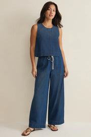 Woman wearing relaxed ankle length straight wide leg pants in a dark blue denim wash with a drawstring and pockets, front view