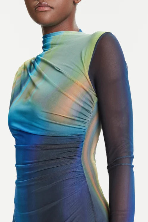 Zoom in of woman wearing a blue and green dress with sheer sleeves on a white background
