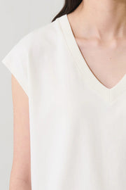 Woman wearing a cream V-neck short-sleeve top with a relaxed fit, detail view