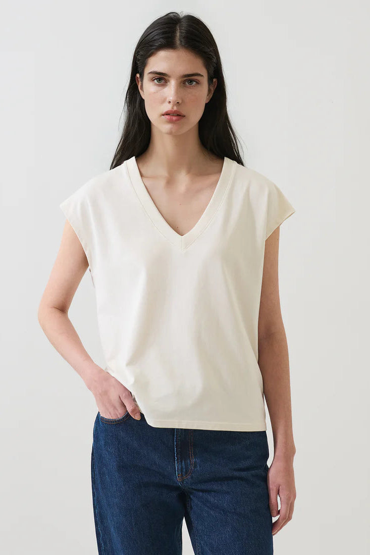 Woman wearing a cream V-neck short-sleeve top with a relaxed fit, front view