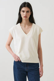Woman wearing a cream V-neck short-sleeve top with a relaxed fit, front view