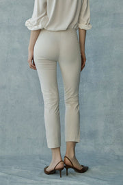 Woman wearing beige high-waisted slim-fit ankle-length pants, back