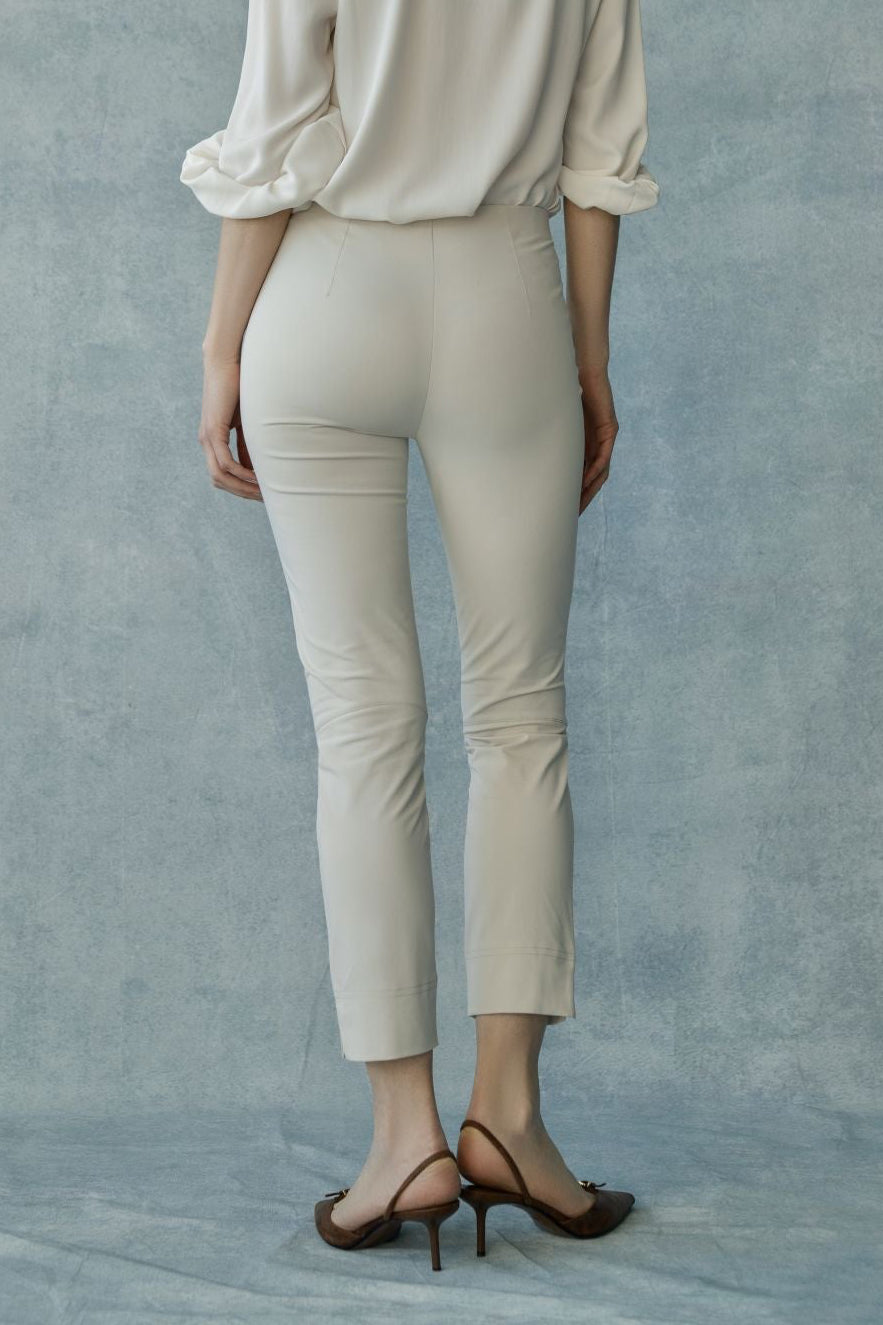 Woman wearing beige high-waisted slim-fit ankle-length pants, back