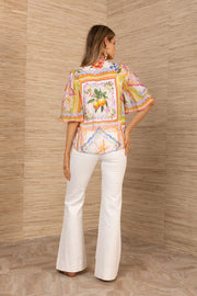 back of a woman wearing orange, pink and ivory half sleeve blouse