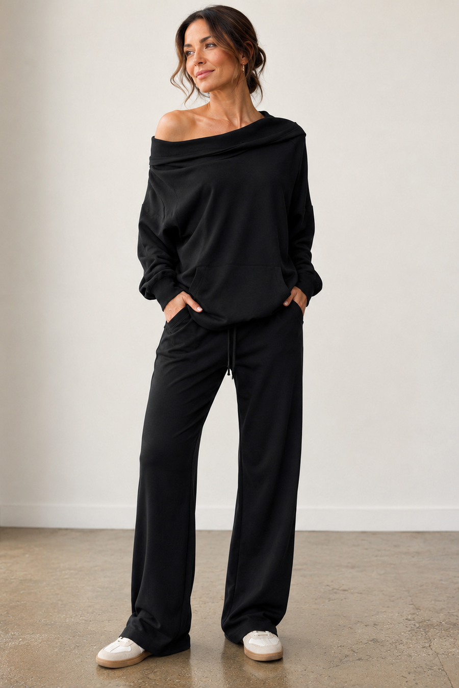 A woman modeling a black off-the-shoulder hoodie