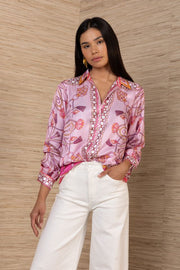 woman wearing a pink silk button down with rouching on the sleeves tucked in