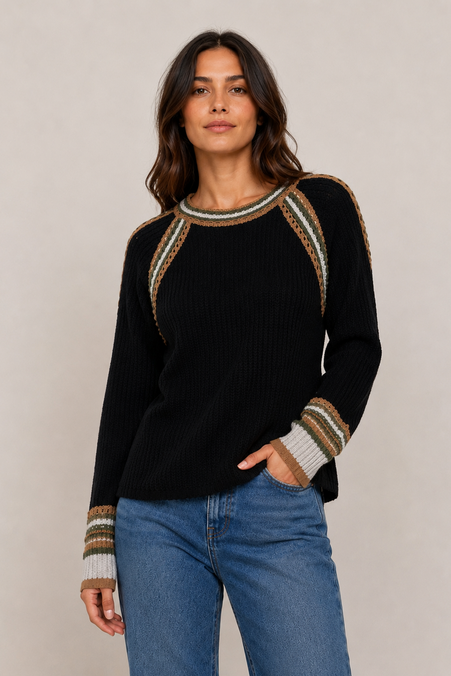 A woman modeling a black ribbed knit sweater with striped and patterned shoulder and cuff details,