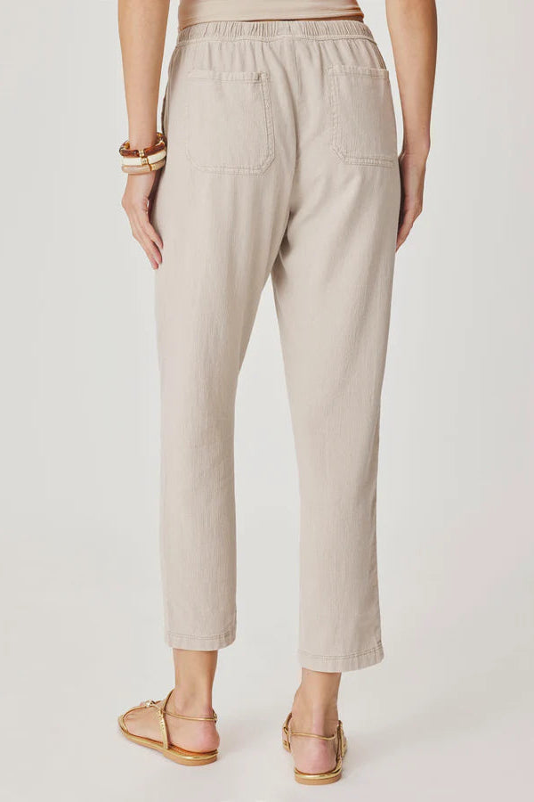 Woman wearing light beige cropped pull-on pants with an elastic drawstring waist, relaxed tapered fit, and front patch pockets, back