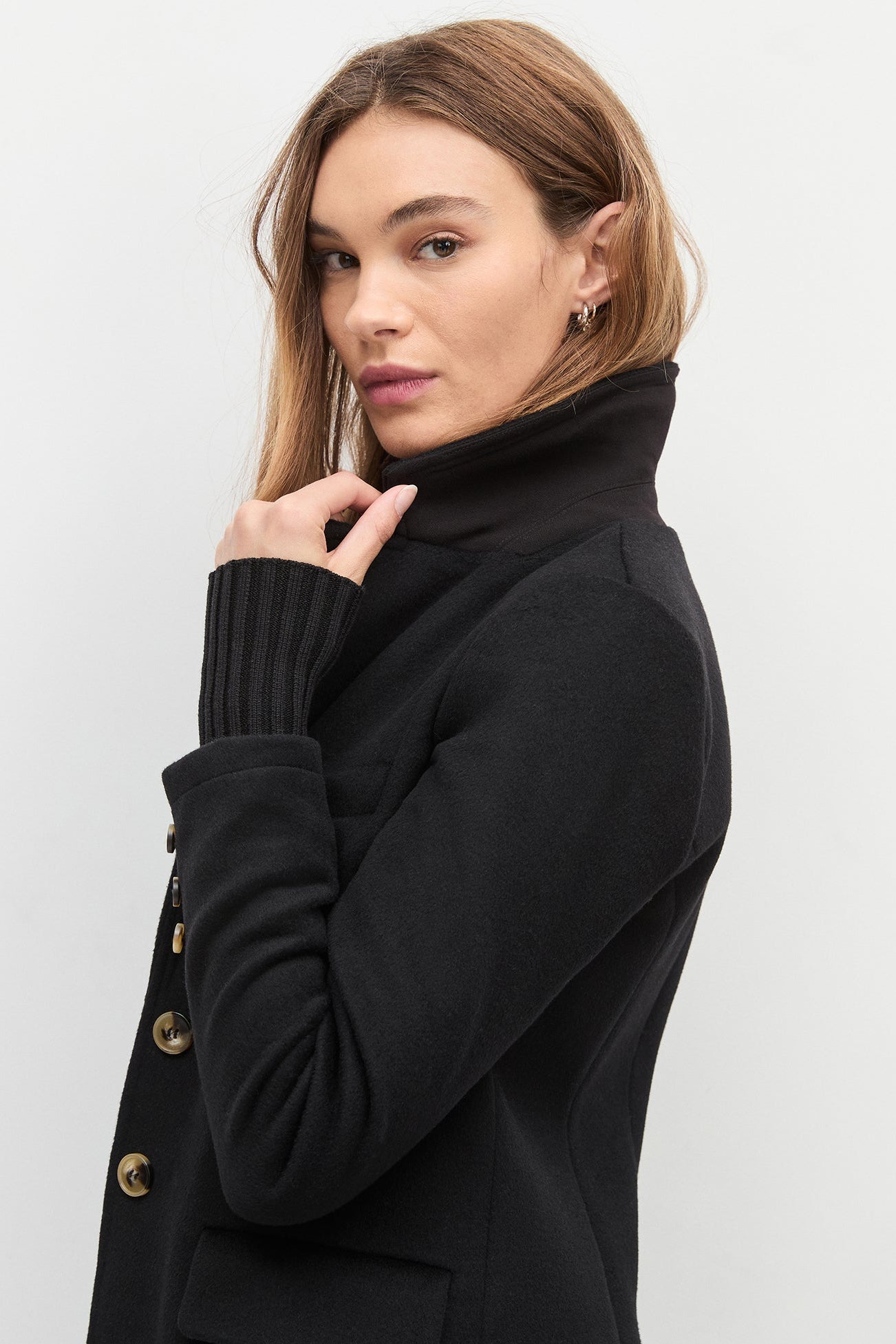 Woman wearing a black coat with a plain background
