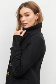 Woman wearing a black coat with a plain background