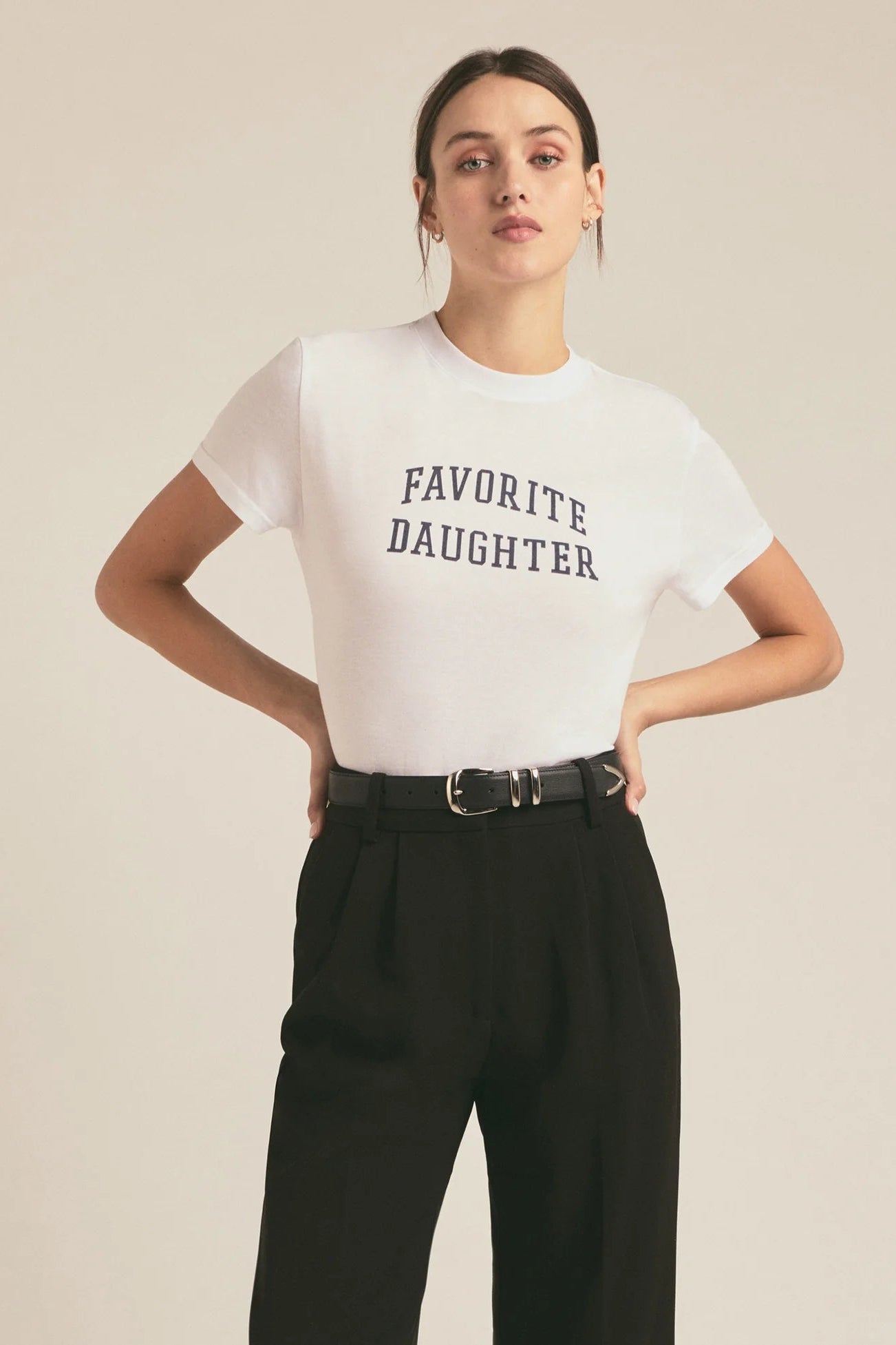 Woman wearing a fitted white graphic t-shirt with “Favorite Daughter” lettering and rolled short sleeves, front