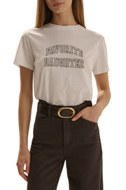 A woman wearing a cream-colored graphic t-shirt with 'FAVORITE DAUGHTER' printed in brown varsity-style lettering