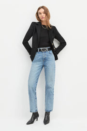 Full body view of a woman wearing a black blazer and blue jeans