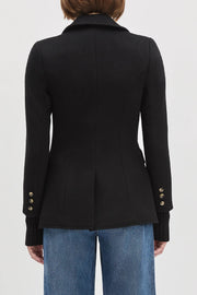 Back view of a woman wearing a black jacket with cuff sleeves, brown top and black jeans