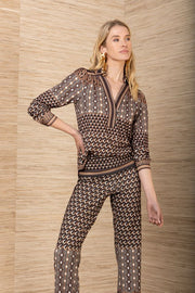 Front view of woman wearing a matching black, brown and mustard yellow patterned blouse and pants with