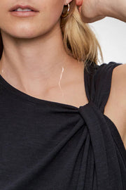 Close-up of a person wearing a black sleeveless top with a white background