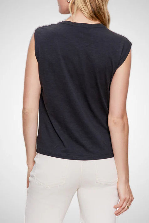 Person wearing a black sleeveless top and white pants on a light gray background