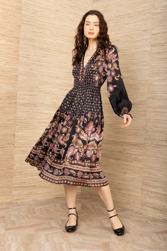 Front view of woman wearing a black, pink and brown patterned long sleeve midi dress