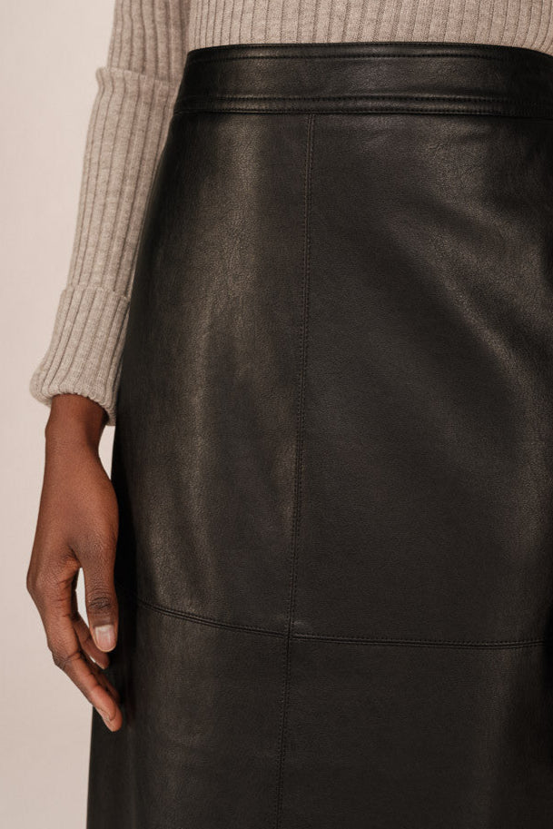 Front  close up view of a person wearing a black leather skirt and black boots