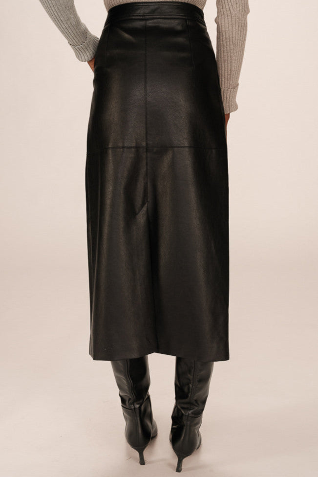 Back view of a person wearing a black leather skirt and black boots