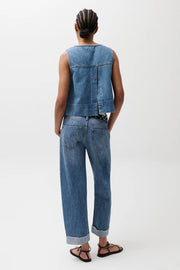 Woman wearing light wash straight-leg jeans with a cuffed hem, back view