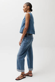 Woman wearing light wash straight-leg jeans with a cuffed hem, side view