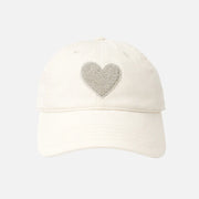 Cream baseball cap with a textured heart detail and “love always” embroidery on the side, front view