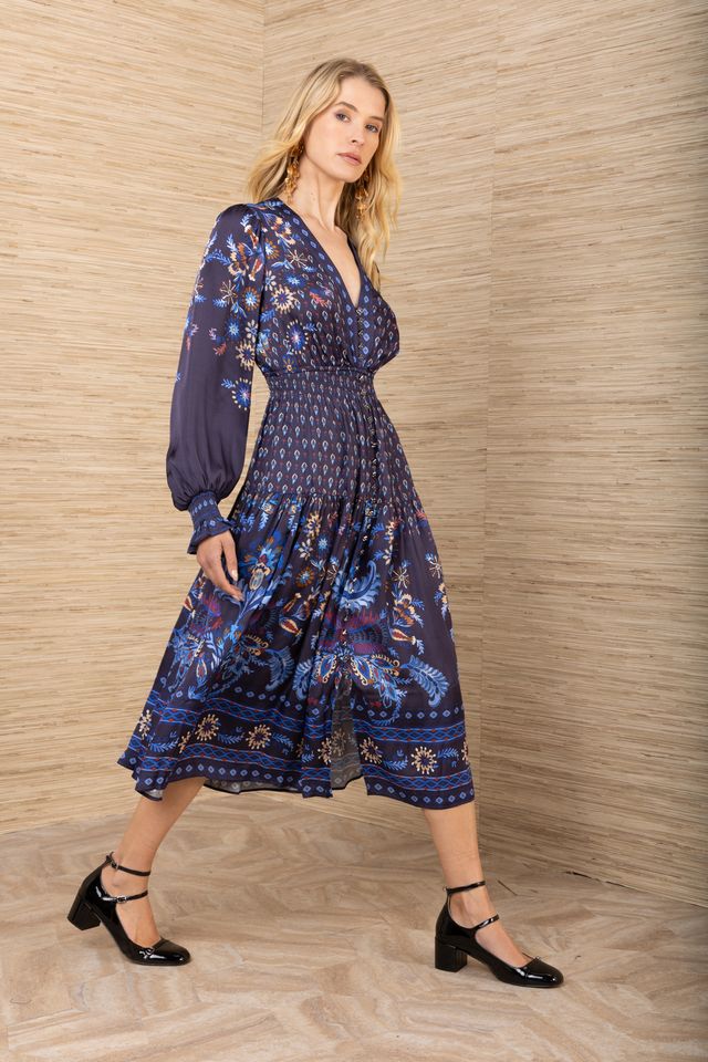 Side view of woman wearing a patterned navy blue long sleeve midi dress