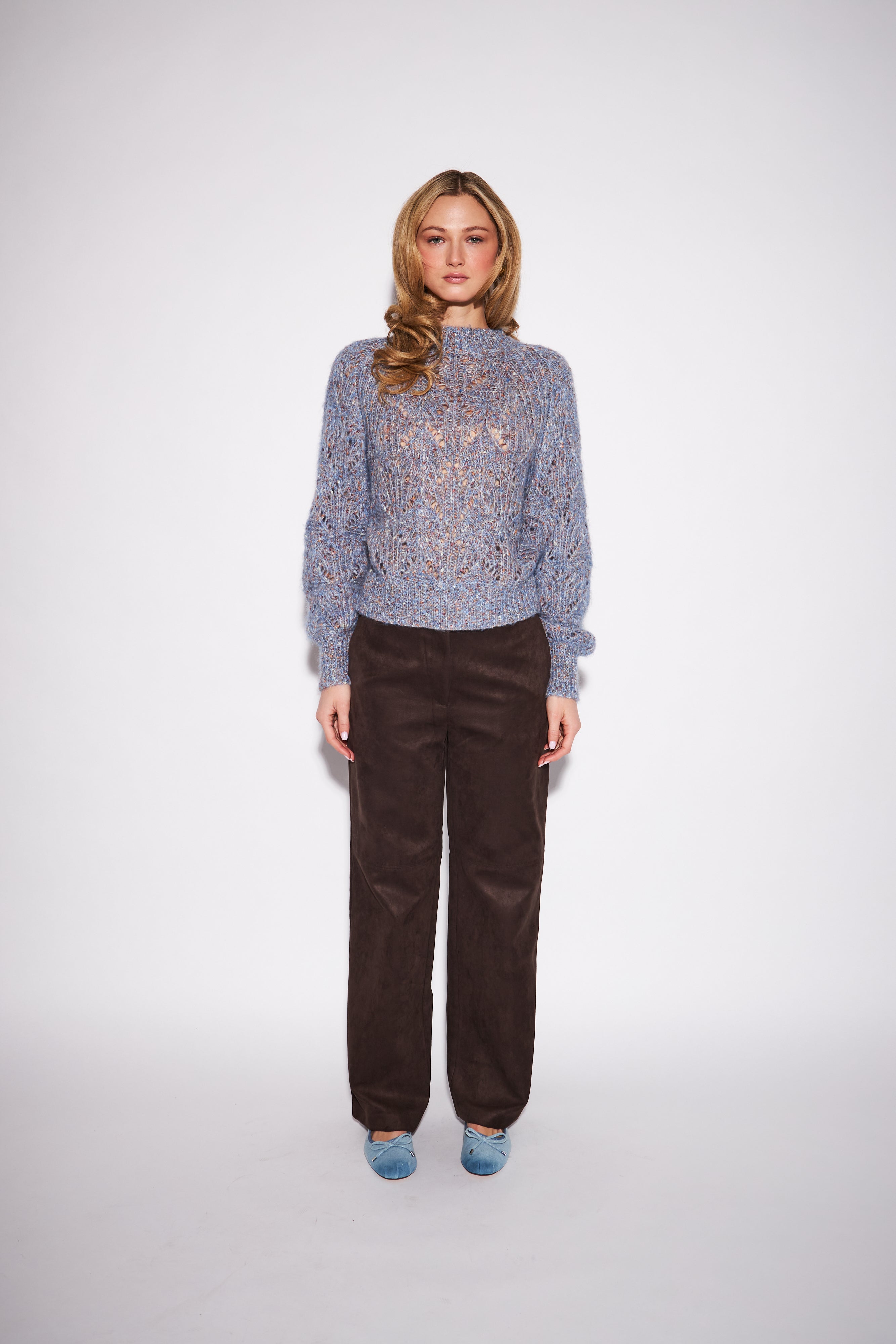 model wearing a blue marled knit mock neck sweater with round balloon sleeves against a neutral studio backround 