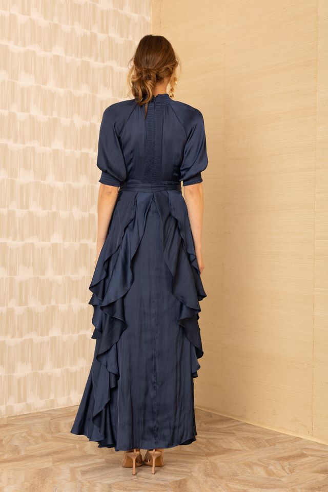 Black view of woman wearing a silk v-neck navy blue dress with ruffles