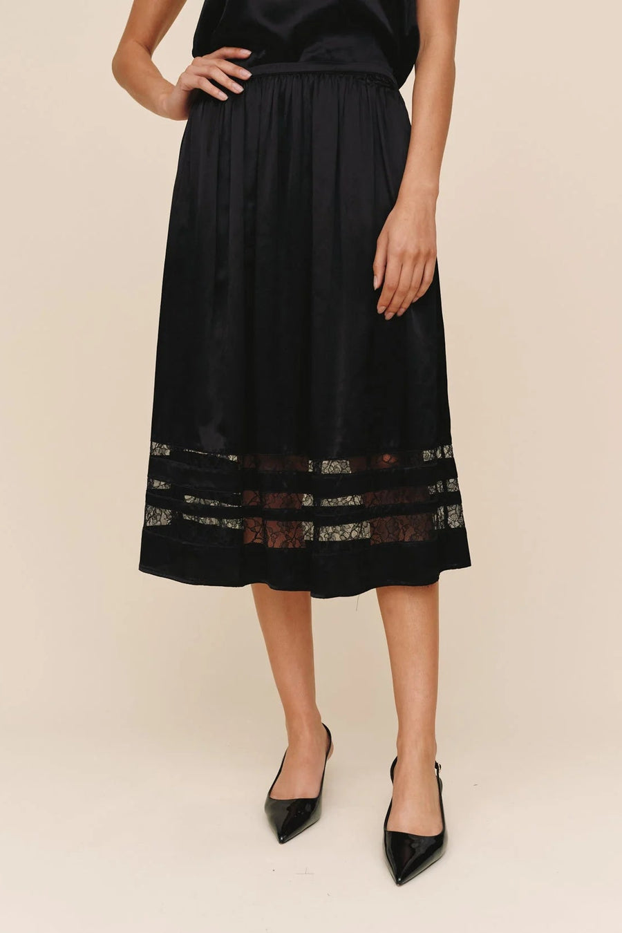 woman wearing a black a-line inset lace midi skirt
