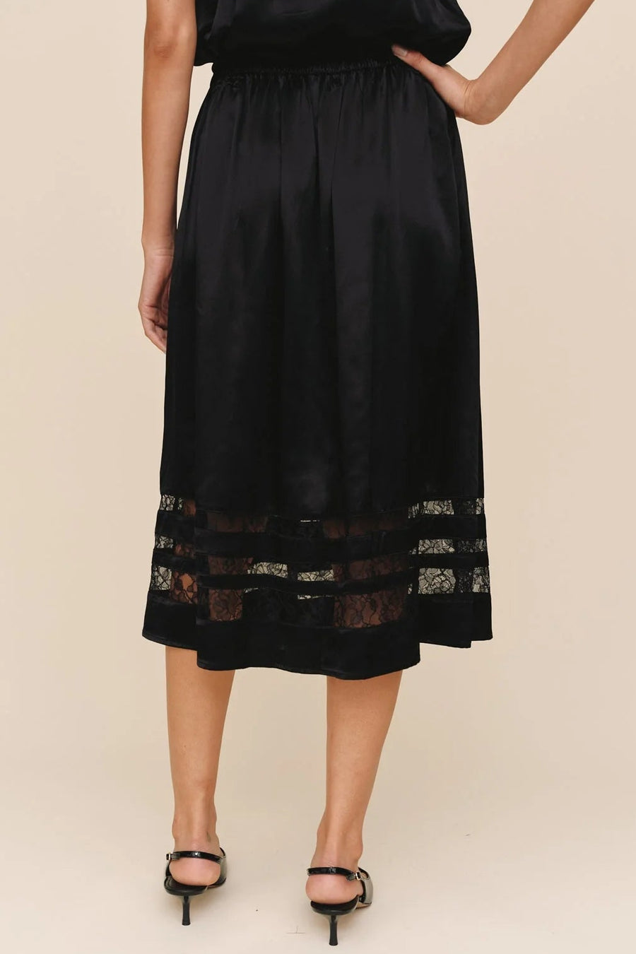 woman wearing a black a-line inset lace midi skirt